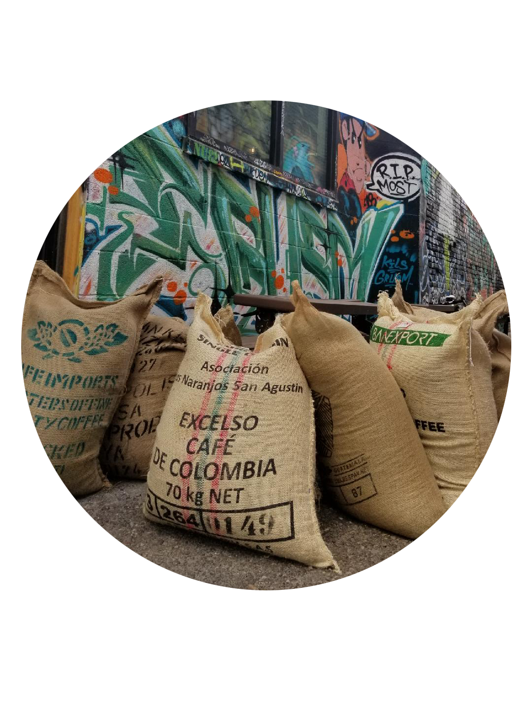 image of large burlap sacks of coffee in front of a graffiti covered wall